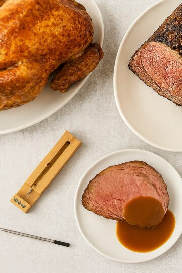 probe meat thermometer on counter with cooke roast of beef and a cooked turkey
