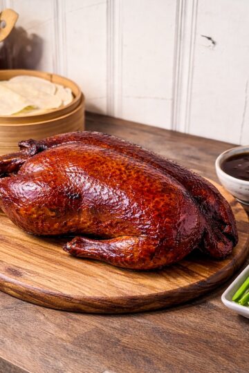 peking duck on a wood tray with spring pancakes, cucumbers and scallions