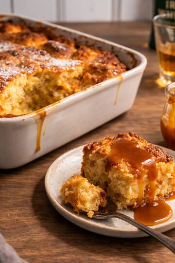 irish bread pudding in a cassarole dish, single serving on a msall plate on a wood countertop