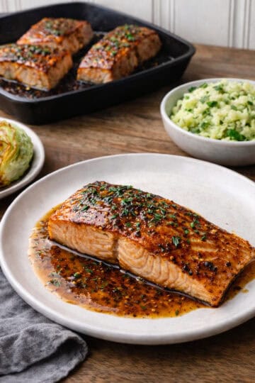 Irish whiskry Galzed Salmon on a white palte, sitting on a wood coutner