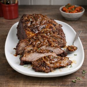 Beef Brisklet braised on a white platter, sliced showing tneder cernter on a wood counter top, small bowl of braised carrots in the backgound