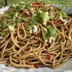cold asian sesame noodle salad, white bowl on a picnic table