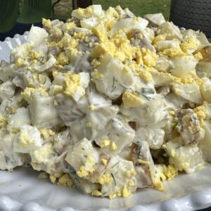 potato salad with fresh dill, hard boiled eggs, creamy dressing in a white bowl