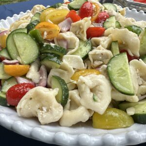 greek village pasta salad, in a white bowl on a picnic table