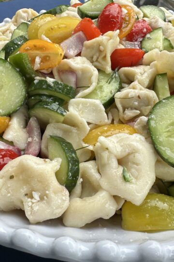 greek village pasta salad, in a white bowl on a picnic table
