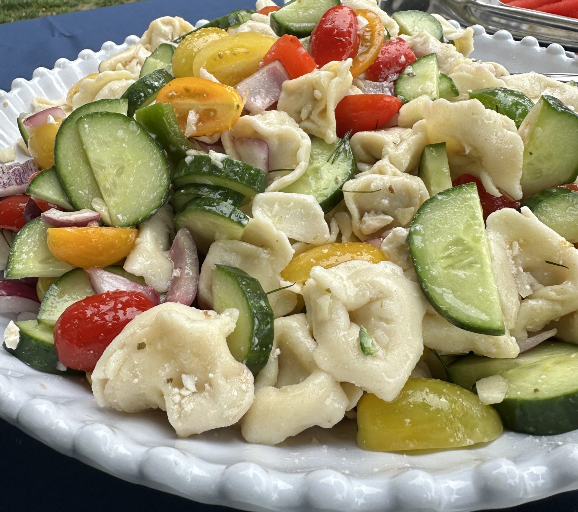 greek village pasta salad, in a white bowl on a picnic table
