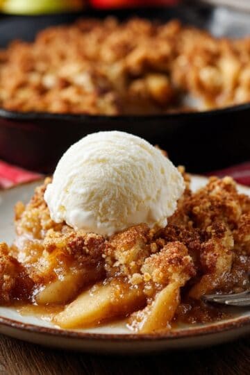apple brown betty with vanilla ice cream, skillet of apple brown betty in the background